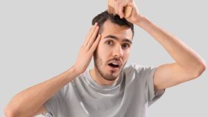 Hombre observando caspa en el cuero cabelludo con expresión de sorpresa