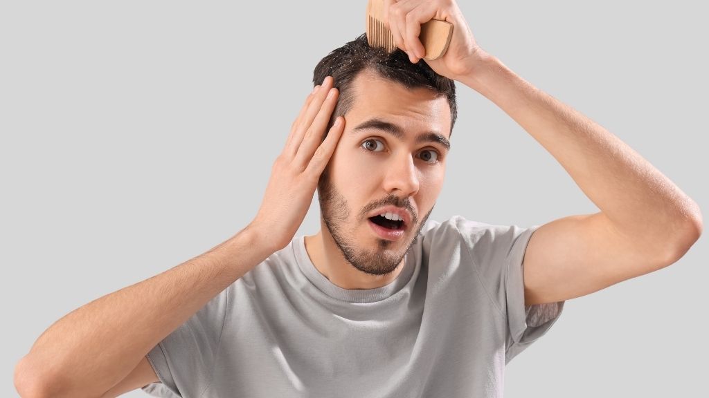 Hombre observando caspa en el cuero cabelludo con expresión de sorpresa