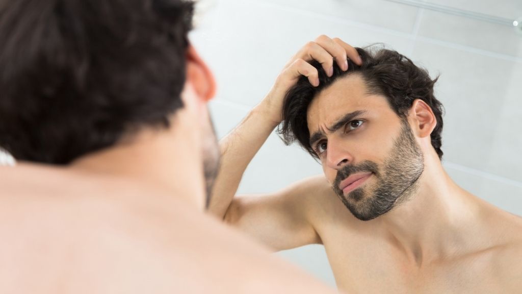 Hombre observando su línea capilar y valorando un injerto capilar.